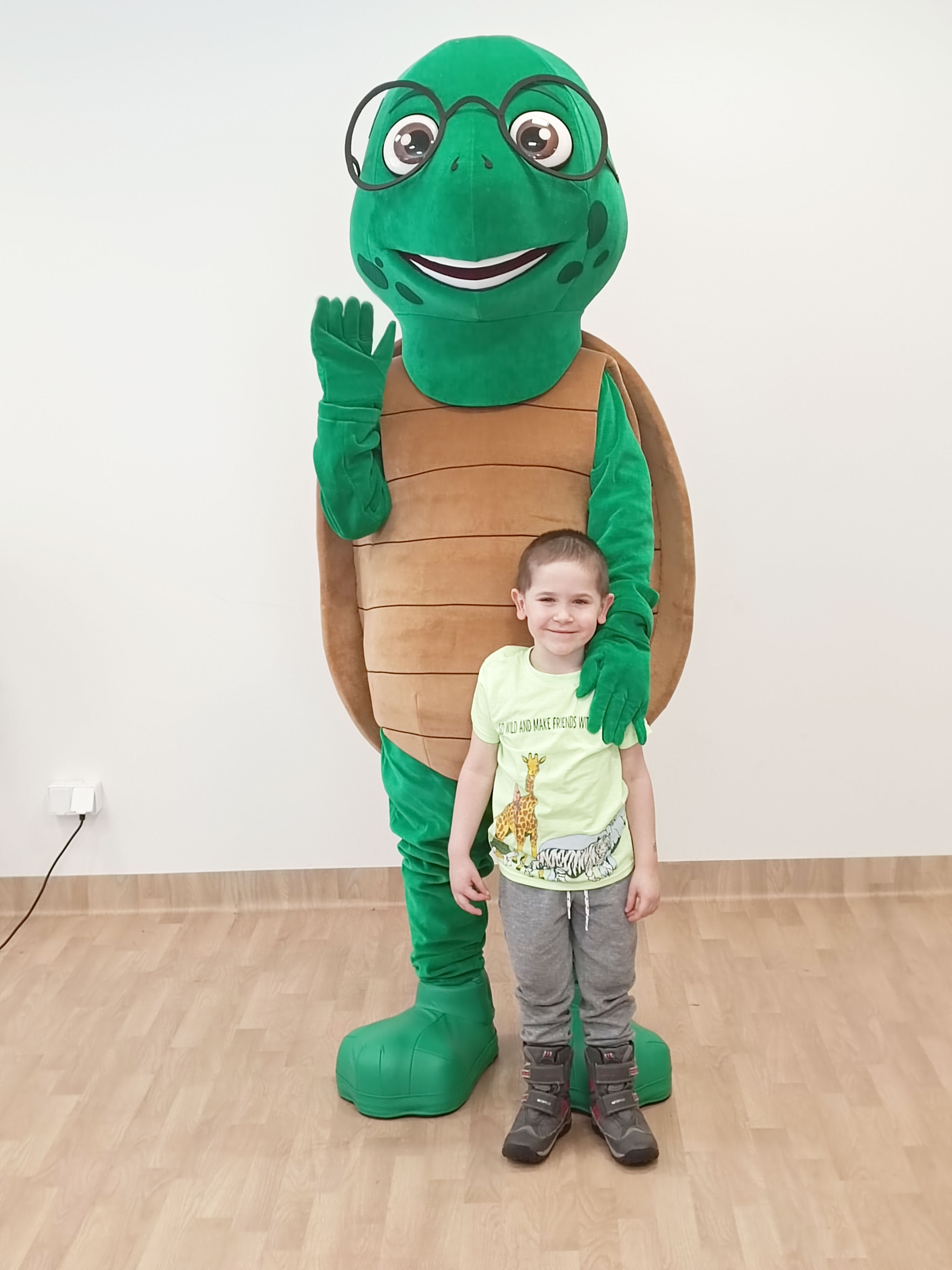 Na fotografii widnieje kostium reklamowy w postaci żółwia pozujący do zdjęcia w siedzibie firmy Elabika